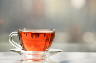 fragrant, red tea in a cup is against the background of the window.
