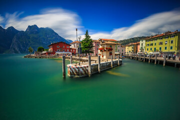 Fototapeta premium Tranquil Waters of Torbole on Lake Garda Surrounded by Colorful Buildings and Mountain Backdrop