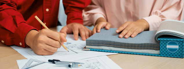 Architect writes curtain material in blueprint, while interior designer selects it carefully on...