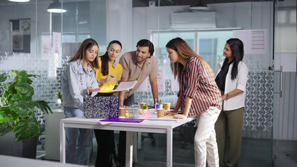 Indian Asian Hindu busy boss lady talk share idea plan use laptop teen girl boy team listen indoor job office young adult gen z female male teach work man staff group leader have client meeting room