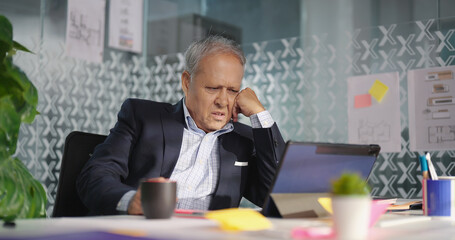 Indian aged older formal dress man expert staff sitting use tablet touch pad talk online video call share ideas plan indoor office old elder busy boss ceo male agent look screen job centre work place