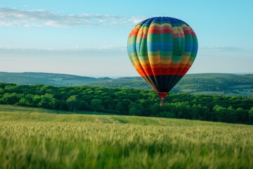 Experience the breathtaking view of a vibrant hot air balloon gracefully floating through the sky, casting a colorful shadow over a picturesque green field.