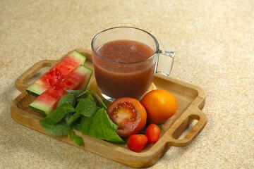 A glass of fresh and healthy juice on wooden tray. Immune booster juice, made from spinach,...