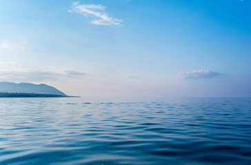 Calming summer natural marine blue background. Sea, mountain and sky with clouds. Copy space, summer vacation concept