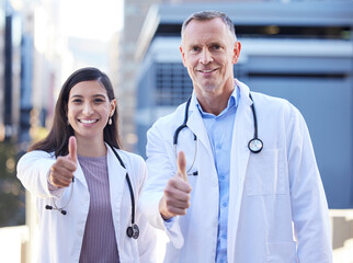 Fototapeta premium Doctors, portrait and thumbs up for medical healthcare by hospital building, approval or agreement. Man, woman and face for happy teamwork or wellness support for insurance trust, goals or service