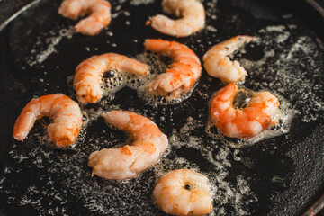 The shrimp is fried in oil in a cast-iron skillet. Large king prawns close-up. Selected focus