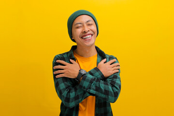 Grateful young Asian man, dressed in a beanie hat and casual clothes, expresses gratitude by...