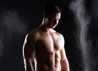 Fototapeta premium Body, fitness and man with abs in studio with chalk, exercise and healthy from training on black background. Bodybuilder, sports or dark for male athlete model, muscular or dust with confident person