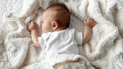 A cute baby lies on a white blanket, legs outstretched, feet in hands.