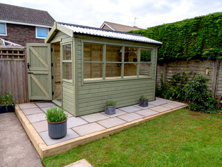 Wooden garden shed on a paved patio in a garden