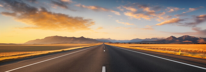 A panoramic view of an asphalt road in a steppe landscape at sunset