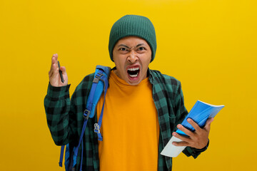 Unhappy young Asian student, dressed in a beanie hat and casual shirt and carrying a backpack, is...