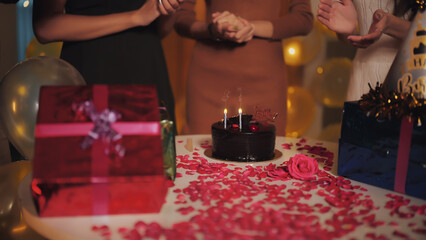 Close up unknown woman lady clap hand chocolate cake on decor rose petal table indoor home. happy girl celebrate joyful special birthday party at house enjoy fun holiday