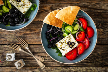 Greek style salad - fresh vegetables with feta cheese, pita bread and black olives served in bowl...