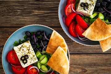 Greek style salad - fresh vegetables with feta cheese, pita bread and black olives served in bowl...
