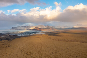 Aerial view of volcanic lava valley covered ash and sand. Mountains, sunset clouds. East Iceland.