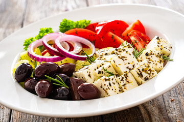 Greek style salad - fresh vegetables with feta cheese and kalamata olives served in white bowl on...