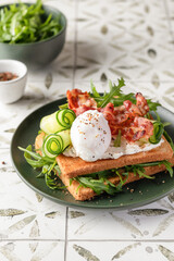 Toasts sandwich with poached egg, cucumber, arugula, bacon and cream cheese on printed tile kitchen background text space