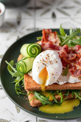 Toasts sandwich with poached egg, cucumber, arugula, bacon and cream cheese on printed tile kitchen background for healthy breakfast close up