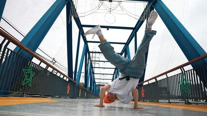 Professional break dancer perform street dance footstep at bridge. Asian hipster wear headphone...