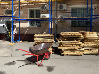 Wheelbarrow and pallet decking at construction site. Local home renovation concept. Mobile phone...