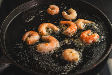 King prawns are fried in boiling oil in a cast-iron skillet. Mediterranean cuisine. Selected focus.