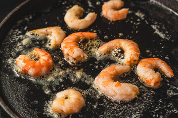 Close-up of large shrimp fried in boiling oil in a cast iron skillet. Delicious Mediterranean food....