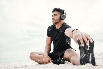 Beach, headphones or man stretching legs with fitness for body flexibility, thinking or wellness on sand. Music, podcast or sports athlete in workout, mobility training or exercise warm up at sea