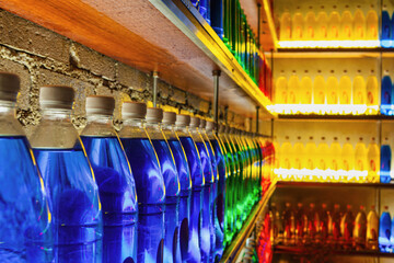 illuminated colorful bottles stacked in shelves, indoors in a bar