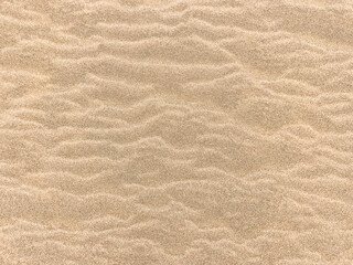 Sand. Texture, surface of sea sand. Natural background. Close-up. Waves of sand. Dunes. Copy space
