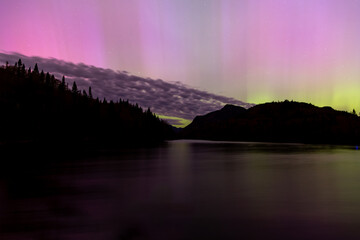 Beautiful magenta and green northern lights reflected in river in the Jacques-Cartier National...