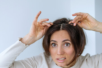Sad look of a woman shows gray hair on her head. Hair with fragments of gray hair, hair roots...