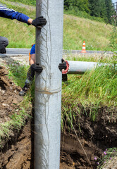 Builders installing utility poles along the rode.
