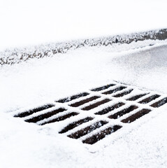 Drain grate covered with snow.