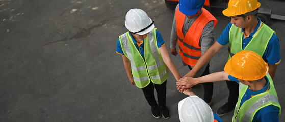 High-angle shot of a group of workers joining hands together, banner cover design with space for...