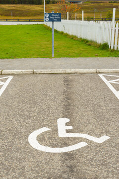 A disabled parking space with symbol and sign in a car park, vertical portrait format