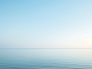 Fototapeta premium Tranquil sea under a clear sky at dawn, with gentle ripples and a soft gradient from blue to light orange.