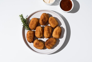 Plato de croquetas fritas con salsa de tomate y mayonesa aperitivo sobre fondo gris y blanco. Vista superior