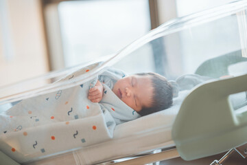 Cute little Asian newborn baby lying in crib in a maternity hospital, Healthcare, Pregnancy and motherhood concept