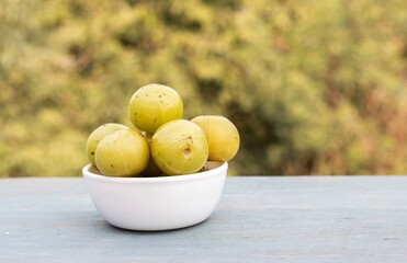 Amla Fruit or Indian Gooseberry Fruit in a White Bowl Isolated on Wooden Table with Copy Space, Also Known as Emblica Myrobalan or Phyllanthus Emblica