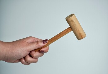 Hand with brown nail polish holding wooden hammer object photography isolated on horizontal ratio...
