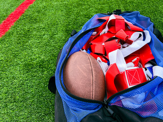 Flag Football Equipment on Green Turf. A large athletic duffel bag is filled with equipment for...