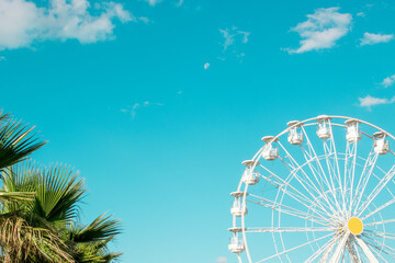 Fototapeta premium The white Ferris wheel against the blue sky. Happy feelings of a summer holiday