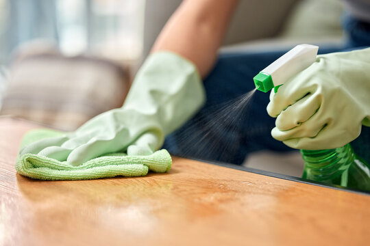 Table, cleaning service and hand of person with bottle for hospitality, work and safety in hygiene. Cloth, spray and cleaner with product in hotel for maintenance, bacteria removal and housekeeping