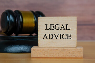 Legal advice text engraved on wooden block with gavel background. Legal and law concept.