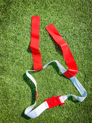 Flag Football Equipment on Green Turf. White belt with red flags and clip used for playing flag...
