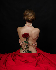 A naked girl is sitting in a red cloth with her back to the frame