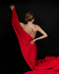 A naked girl stands with her back covered with a red cloth
