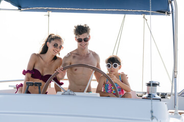 Mother and Father teaching their daughter how to drive speedboat or yacht, concept of family...
