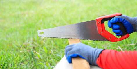 hand using saw in wood cutting working in daily life. safety using handsaw with gloves